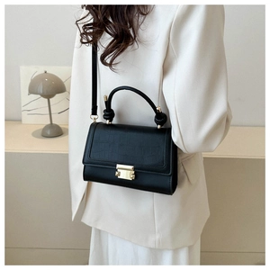 Detail of black croc-effect small square bag with golden lock and twisted top handle