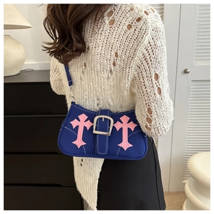 Detail of royal blue canvas shoulder bag with pink cross appliques and silver buckle