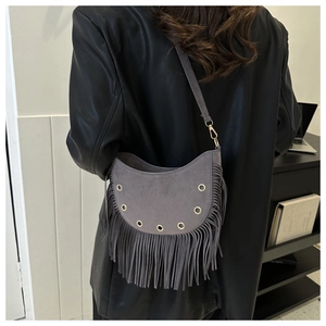 Detail view of the grey crescent bag featuring long suede fringe and gold metal eyelets