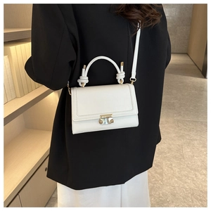 Detail showing white crocodile texture crossbody bag with knot handle and gold buckle