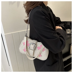 Detail of canvas baguette bag with pink gothic cross embroidery and silver metal chain