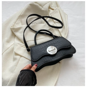 Détail du sac à main noir motif crocodile avec base incurvée et fermoir en métal argent