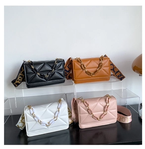 Detail of four colorful quilted crossbody bags with chain decor and wide woven straps