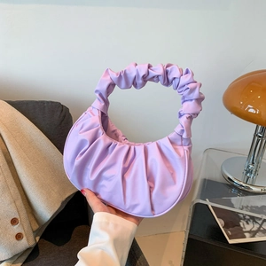 Purple pleated dumpling bag with ruched handle shown in a stylish lifestyle setting