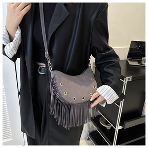 Detail of grey suede crescent bag featuring long tassels and metallic eyelet accents