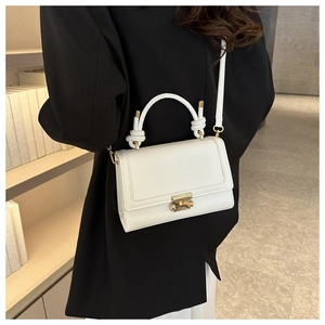 Detailed shot of white leather crossbody bag featuring knot handle and gold metal clasp