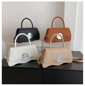 Détail de quatre sacs à main colorés en similicuir crocodile avec bord inférieur ondulé