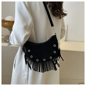 Detailed view of black suede crossbody bag featuring fringe trim and metal eyelet accents