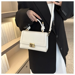 Detail of white crocodile embossed mini bag with knot handle and gold hardware