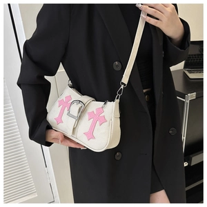 Detail of white canvas bag featuring pink cross embroidery and silver metal buckle