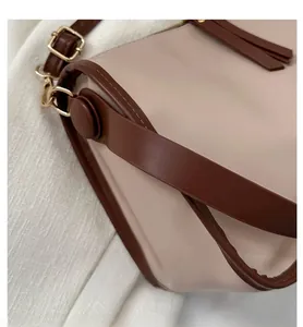 Detail shot of beige PU leather bag with dark brown trim and golden metal buckles