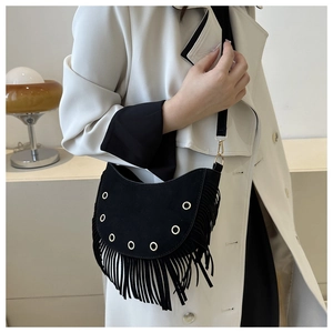 Close-up of black suede moon bag featuring silver eyelets and long bohemian tassels