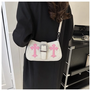 Close-up of pink gothic cross patches and contrast stitching on a chic underarm bag