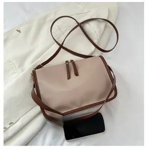 Detail view of small square shoulder bag showing compact size with smartphone comparison