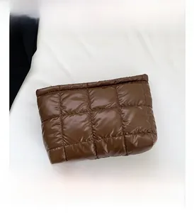 Macro shot of dark brown quilted puffer handbag with a glossy finish and square patterns