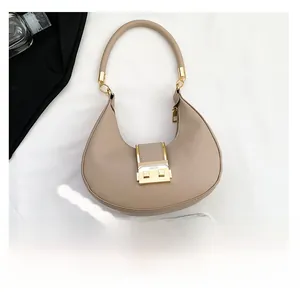 Detail view of crescent underarm bag showing golden buckle and size comparison with phone