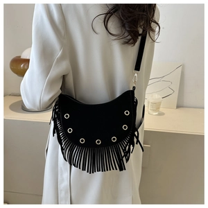 Detail shot of a black crescent tassel bag on a model wearing an elegant beige coat