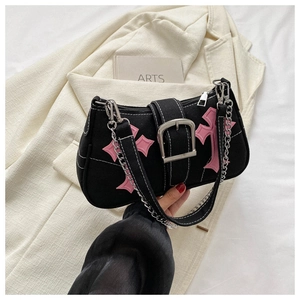 Detail of black canvas baguette bag featuring pink cross patches and silver chain strap