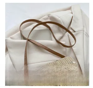 Close-up of straw crossbody bag with floral embroidery and brown leather strap