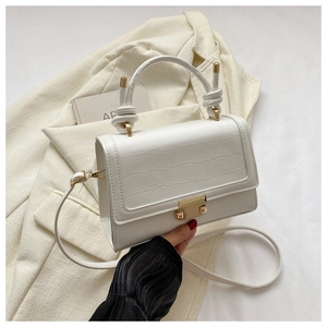Detail of white crocodile-embossed mini bag with unique knotted handle and gold buckle