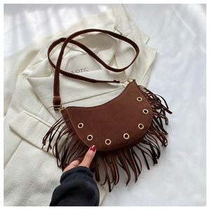 Detail of dark brown suede crescent bag featuring long tassels and gold metal eyelets