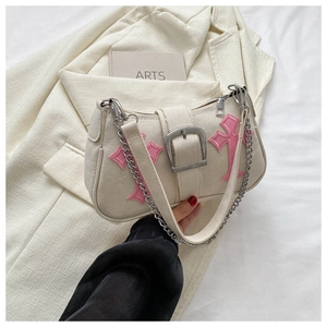 Detail of canvas underarm bag featuring pink cross patch and silver metal buckle