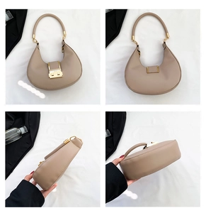 Detail view of the beige half-moon bag featuring polished gold metal clasp and smooth leather