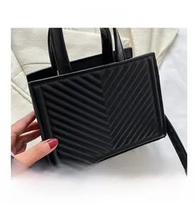 Detail of black V-quilted faux leather tote bag with sturdy handles and shoulder strap