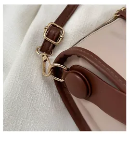 Detailed macro view of golden metal hooks and precise stitching on the leather tote bag