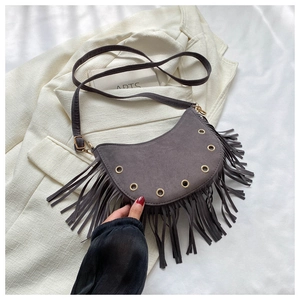 Detail of grey suede crescent bag with hanging fringe and metallic eyelet accents