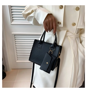 Detail of black quilted tote bag with metallic handles and small matching purse charm