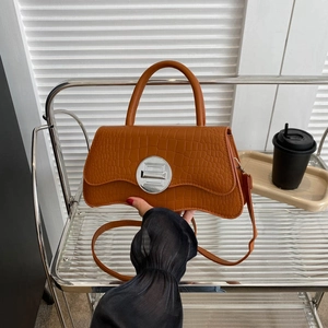 Sac à main caramel motif crocodile avec base ondulée et boucle argentée porté par mannequin