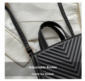 Close-up of black quilted handbag with golden buckle and V-shaped texture details