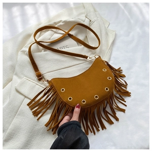 Detail of tan suede crescent bag featuring long tassels and gold eyelet decorations