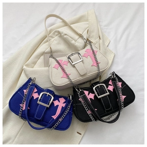 Detail of canvas underarm bags with gothic cross patches and silver buckle hardware