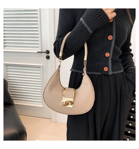 Close-up of the beige crescent shoulder bag featuring a gold square metallic clasp