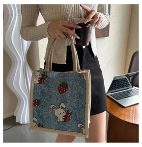 Detailed close-up of a linen tote bag with rabbit and strawberry jacquard embroidery