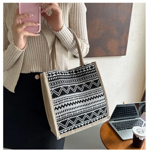 Close-up of geometric pattern weave on linen tote bag with brown handles