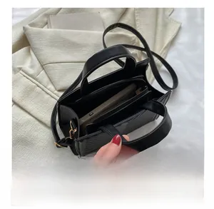 Detail view of the interior compartment and lining of the black textured crossbody bag