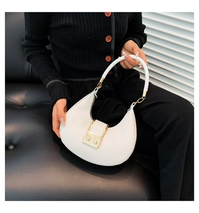Detailed close-up of a white crescent shoulder bag featuring a gold rectangular buckle