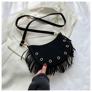Detail of black faux suede half-moon bag featuring long fringes and golden metal eyelets
