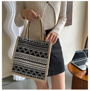 Close-up of geometric pattern tote bag held by a model in a cozy lifestyle setting