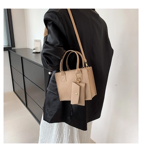Detail of beige quilted tote bag with a small detachable pouch and metallic strap buckles