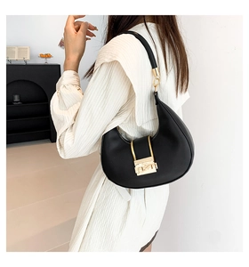 Detail of black leather hobo bag with gold metal buckle shown in a lifestyle setting