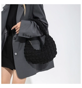 Dettaglio del tessuto a bolle nero su una borsa a tracolla minimalista a mezza luna