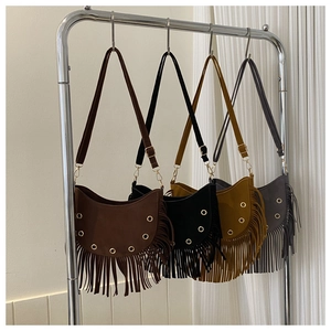 Close-up of bohemian crescent moon bags with fringe tassels in multiple earth tones