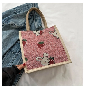Detail of red woven mini tote bag featuring cute rabbit and strawberry prints