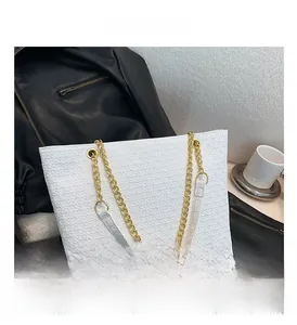 Detalle del bolso tote blanco con relieve de estrellas y correas de cadena dorada