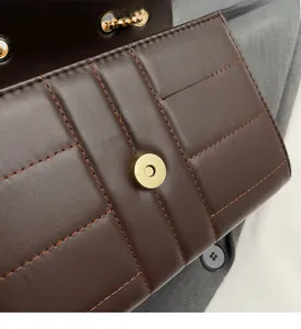 Close-up of dark brown quilted leather texture and shiny gold magnetic hardware clasp