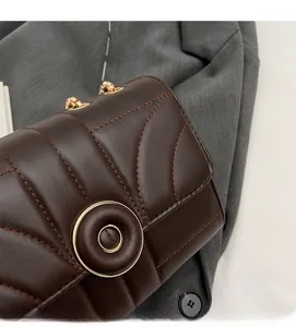 Detail of dark brown quilted leather surface with elegant gold metal round clasp